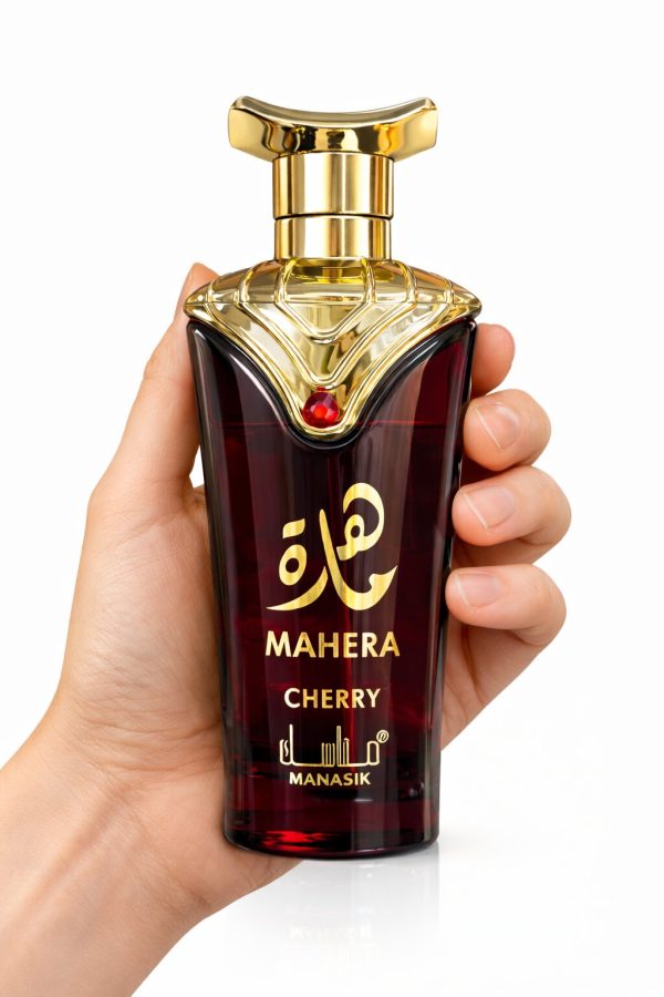 Парфюм Mahera Cherry, държан в ръка, с тъмночервено стъкло и златни детайли