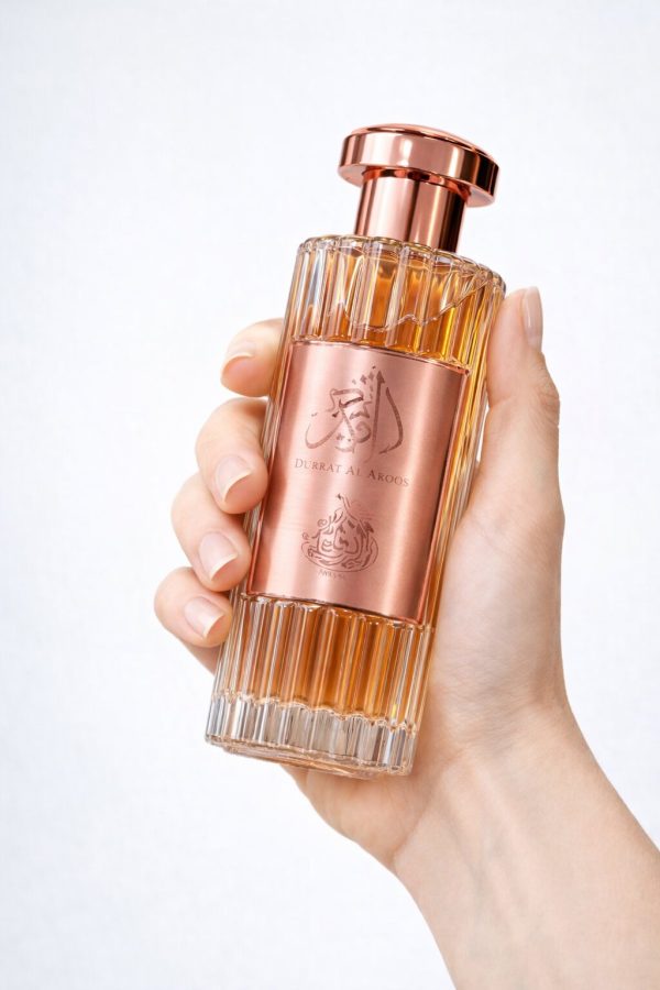 Парфюм Durrat Al Aroos Eau de Parfum, държан в ръка, със стъклен флакон и златисти детайли